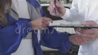 女孩汽车机械师在汽车服务中拍摄汽车数据，并签名拿起钥匙和握手